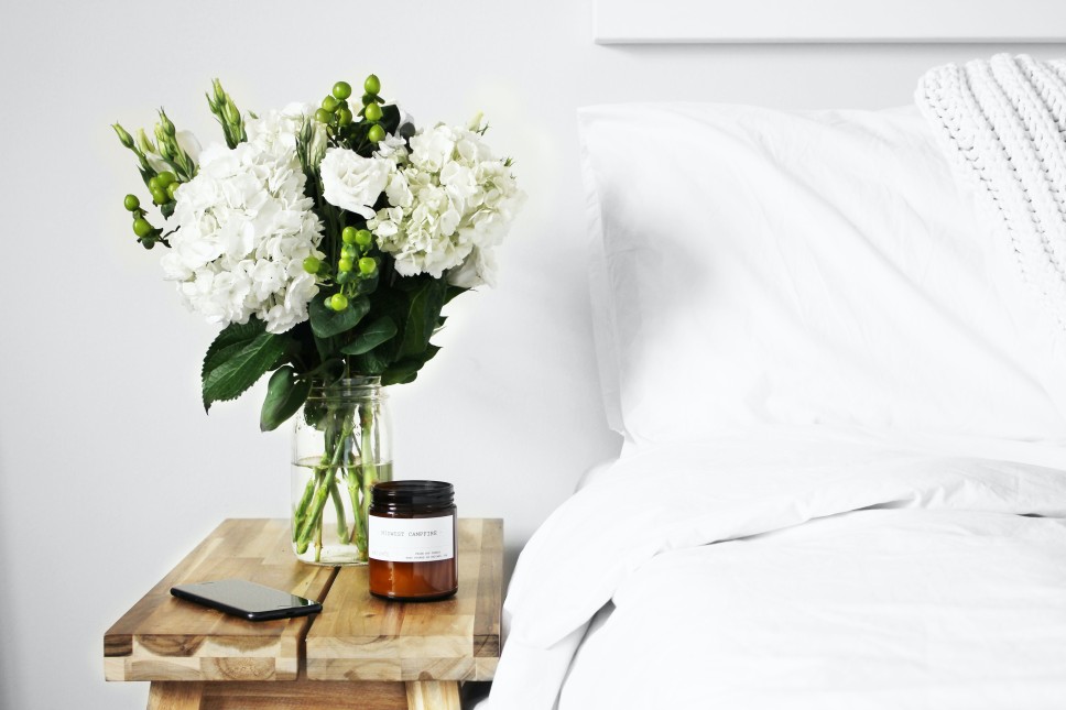 White bed with flowers on night stand
